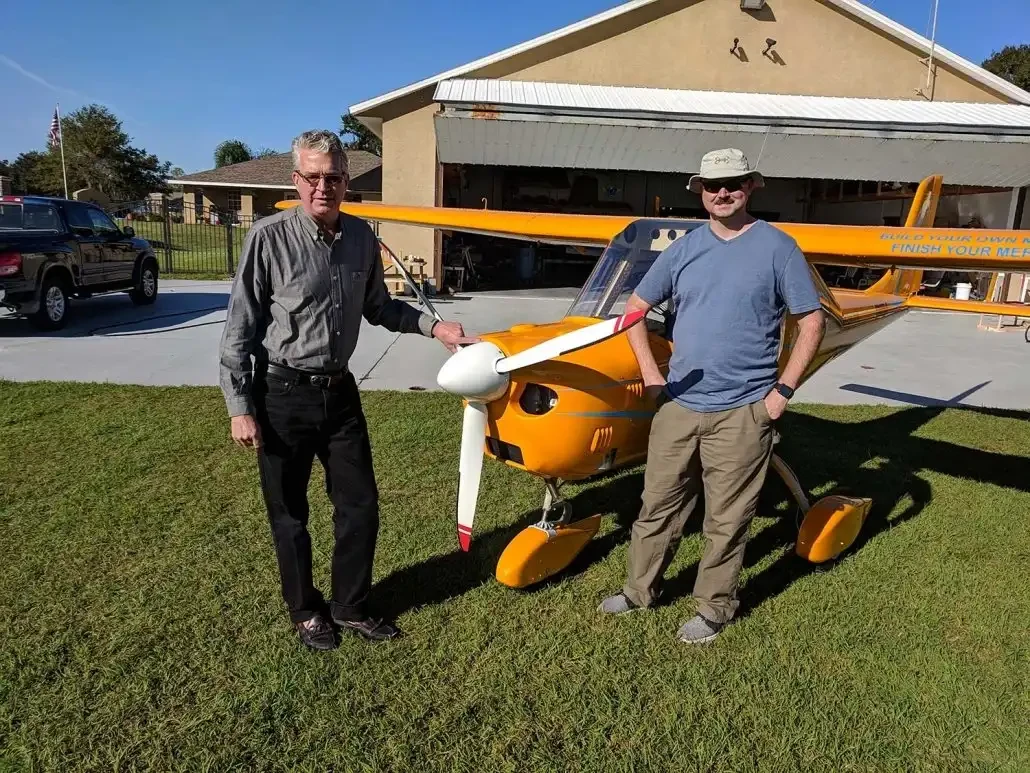 A conversation beside a yellow Merlin at the hangar